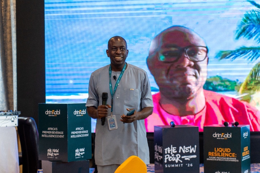 Speaker on stage beside their portrait on screen